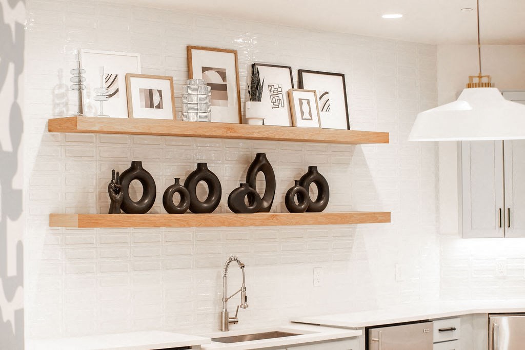a kitchen with white tiles and wood shelves