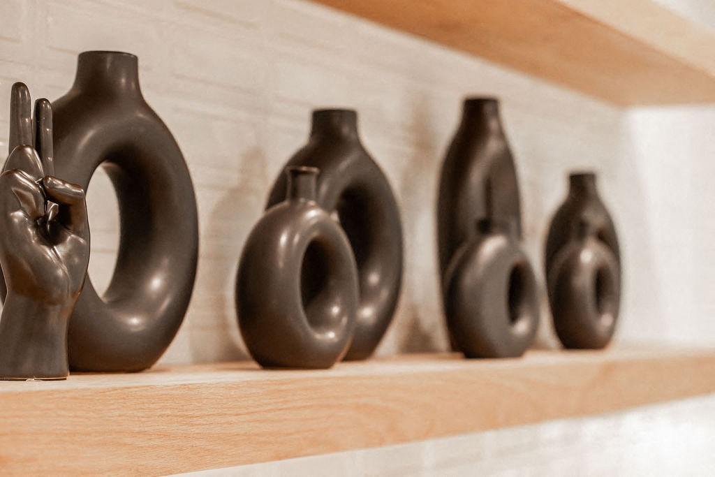 a row of black vases sitting on a shelf
