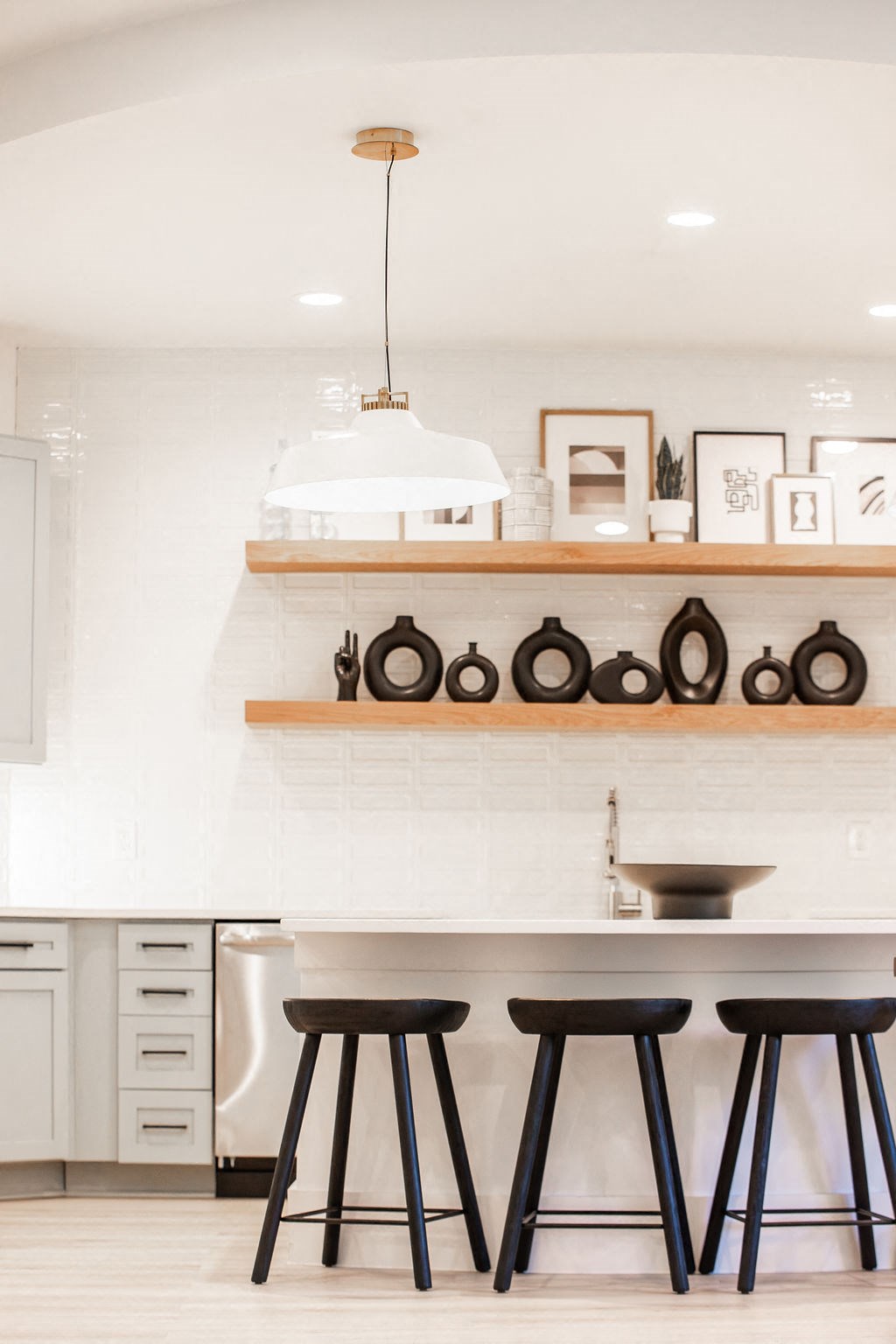 a white kitchen with black stools and a counter top