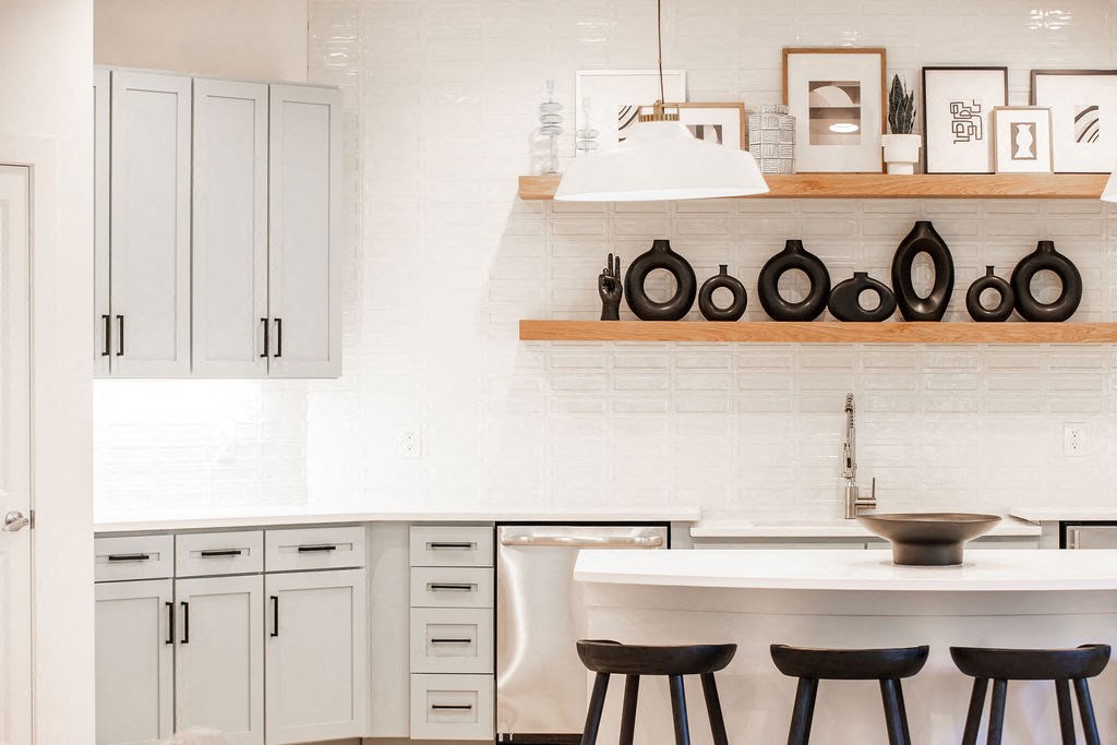 a kitchen with white cabinets and a table with black chairs