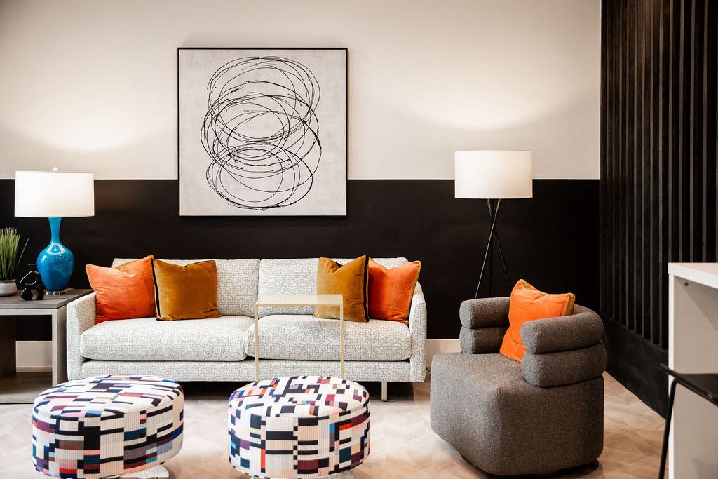 a living room with a couch and chairs and a painting on the wall