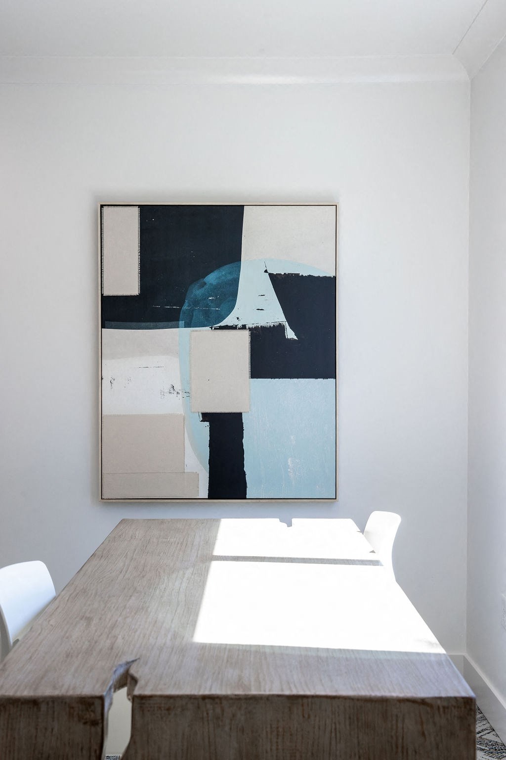 a painting hangs on the wall above a desk in a room