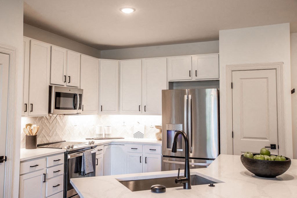 a white kitchen with stainless steel appliances and white cabinets