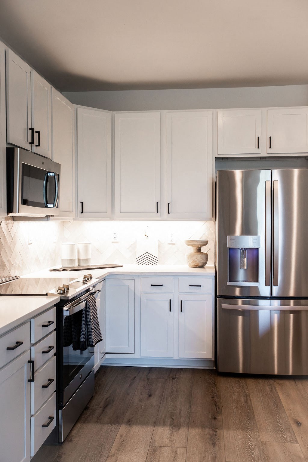 a white kitchen with stainless steel appliances and white cabinets