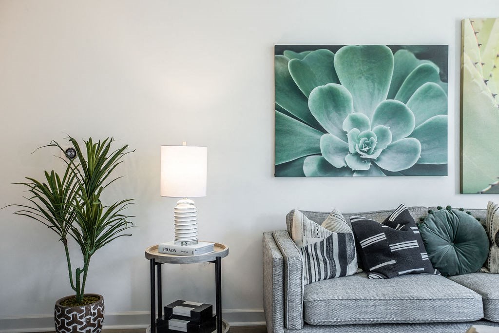 a living room with a couch and a painting of a succulent plant