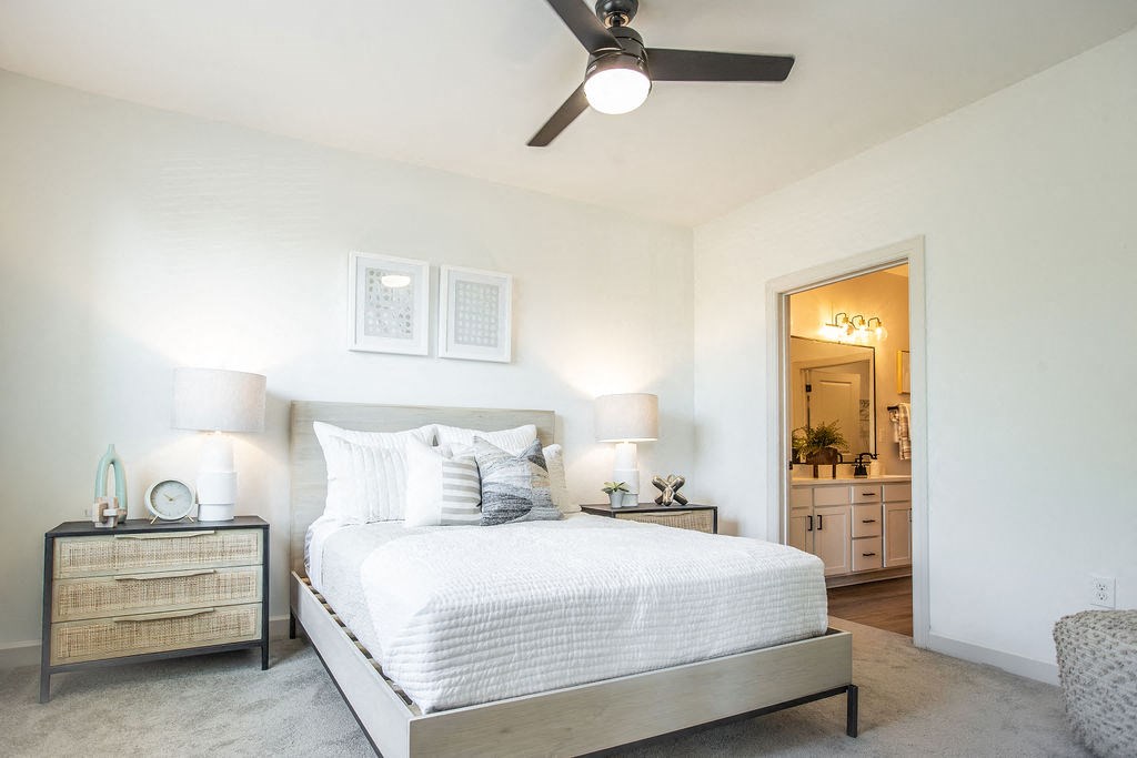 a bedroom with a white bed and a ceiling fan