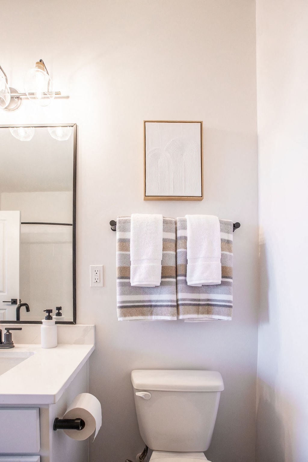 a small bathroom with a white toilet and white and gray towels
