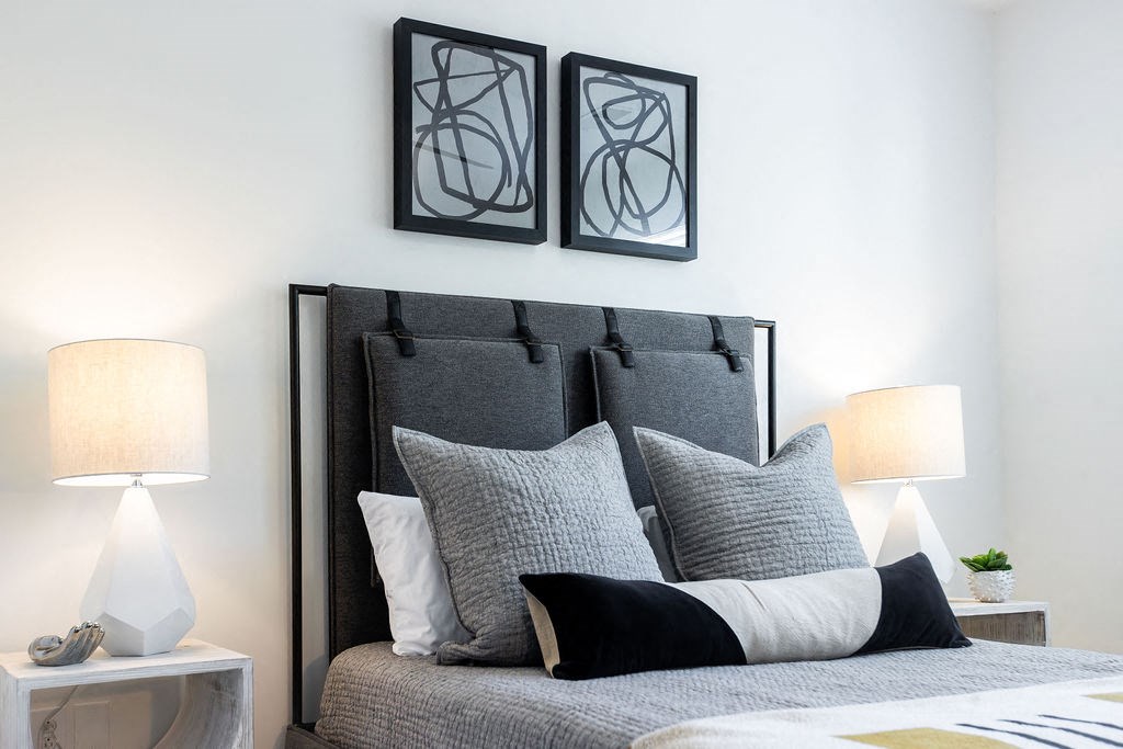 a bedroom with a bed with pillows and artwork on the wall