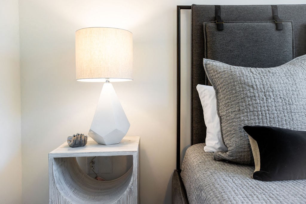 a bedroom with a bed and a nightstand with a lamp