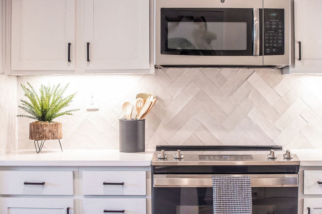 a kitchen with white cabinets and a stove and a microwave