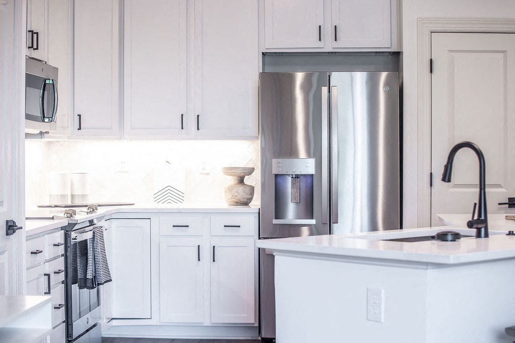 a white kitchen with stainless steel appliances and white cabinets
