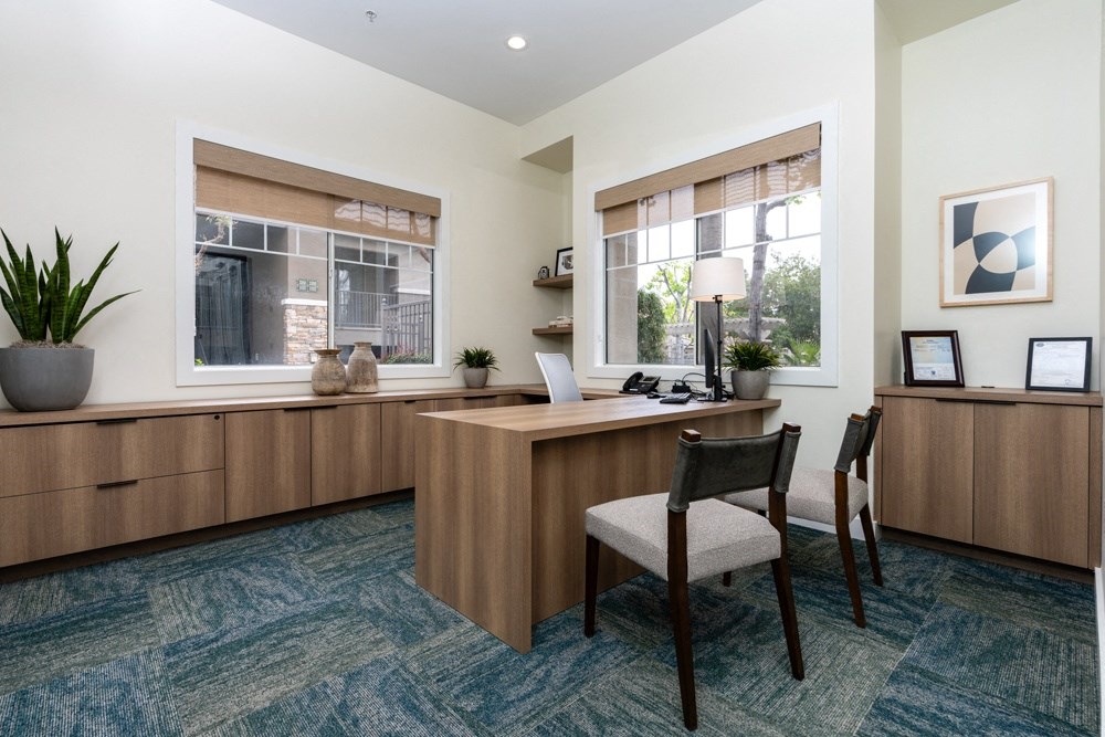 an office with a desk and chairs and a window