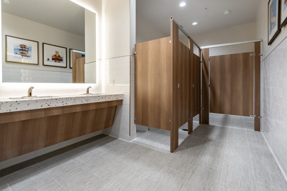 a large bathroom with a long counter and a row of stalls