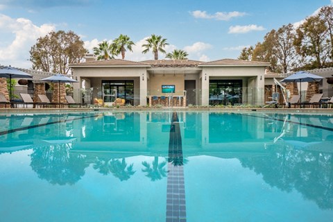 Pool at Camino Real Apartments reflecting the palms, with the clubhouse and its covered patio across the water.