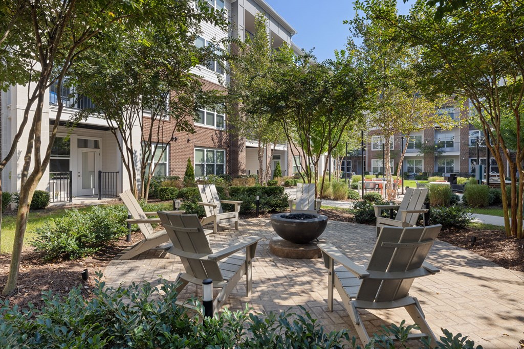 A garden with chairs and a fire pit in front of apartment buildings.