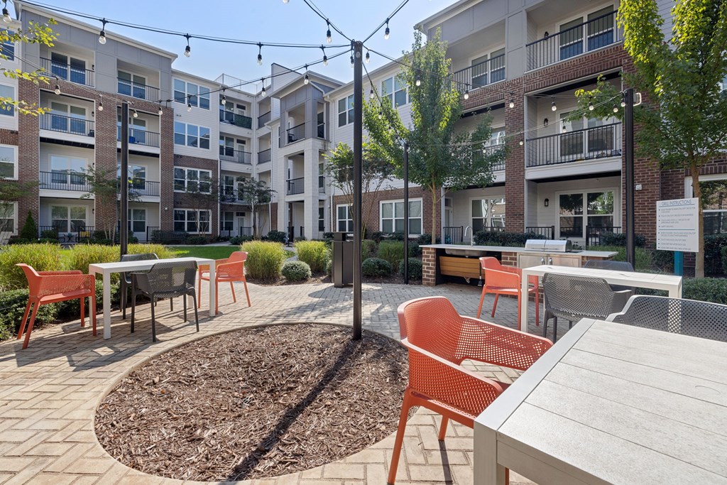 A courtyard with tables and chairs surrounded by apartment buildings.