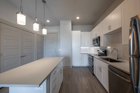 Island Kitchen with Quartz Countertops, White Cabinetry, and Pendant Lights