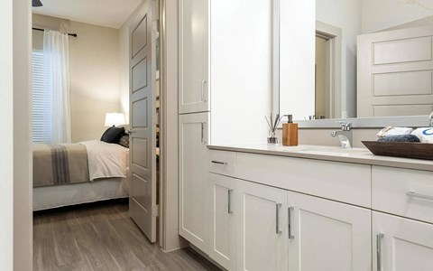 Connected Bathroom Featuring Double Vanity and Linen Cabinet