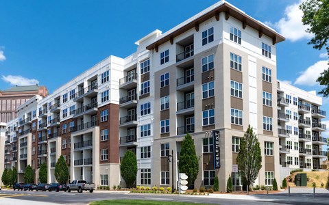 Six-story exterior at The Elden Galleria with private balconies, mixed brick and panel cladding, and a blade sign.