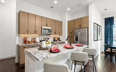 Apartment Kitchen with Granite Island, Bar Stools, and Stainless Appliances Apartment Kitchen with Granite Island, Bar Stools, and Stainless Appliances