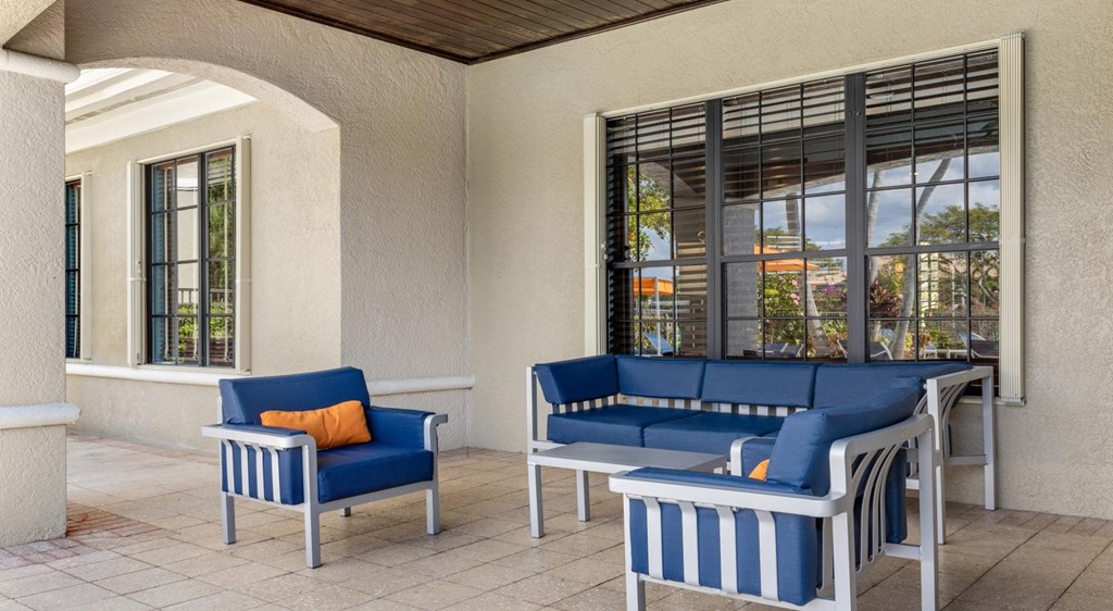 A blue and white striped sofa and chair are on a patio.