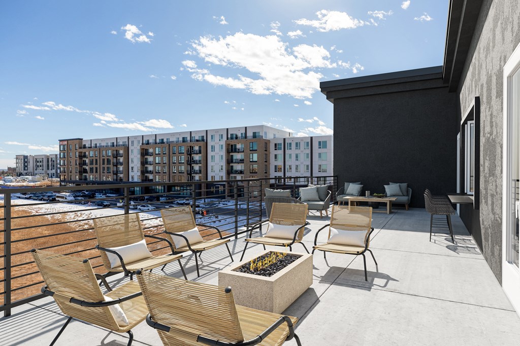 the deck of a building with chairs and a fire pit