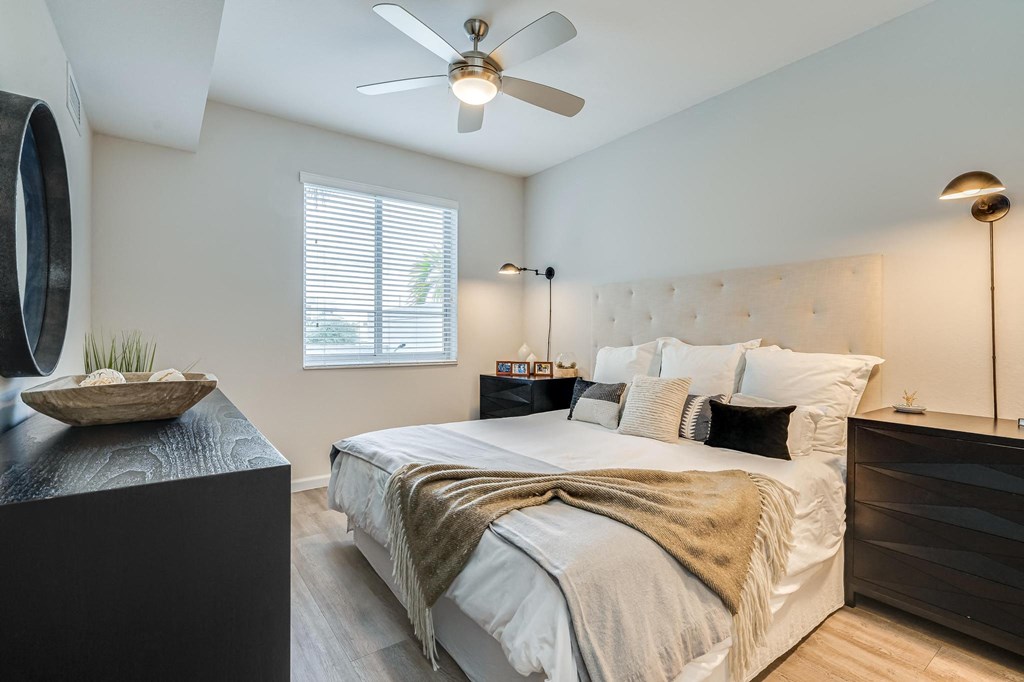 Bedroom Featuring Ceiling Fan, Tufted Headboard, and Window with Blinds