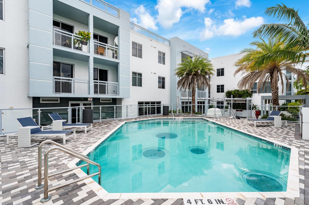 Pool Area Surrounded by Palm Trees and Chaise Seating
