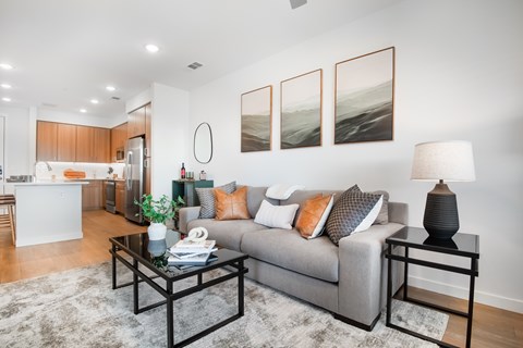 A modern living room with a grey couch, a black coffee table, and a large painting on the wall.
