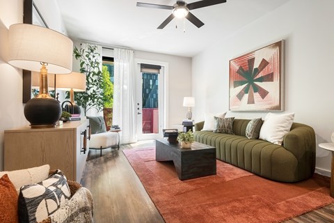A living room with a green couch and a red rug.