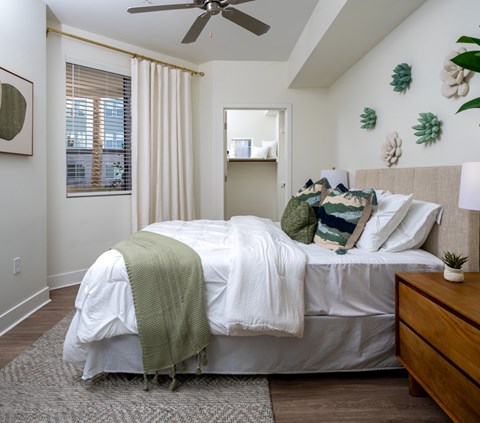 A bedroom with a bed covered in a white comforter and a green throw blanket.