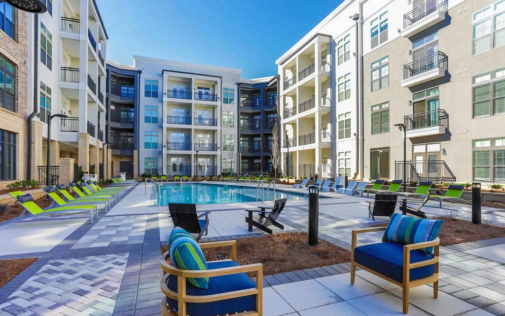 Community Pool with Lounge Seating, Patio Tables, and Apartment Views