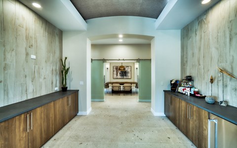 Coffee bar corridor with stone-clad walls, dark counters, a brewing station and a glass beverage refrigerator.