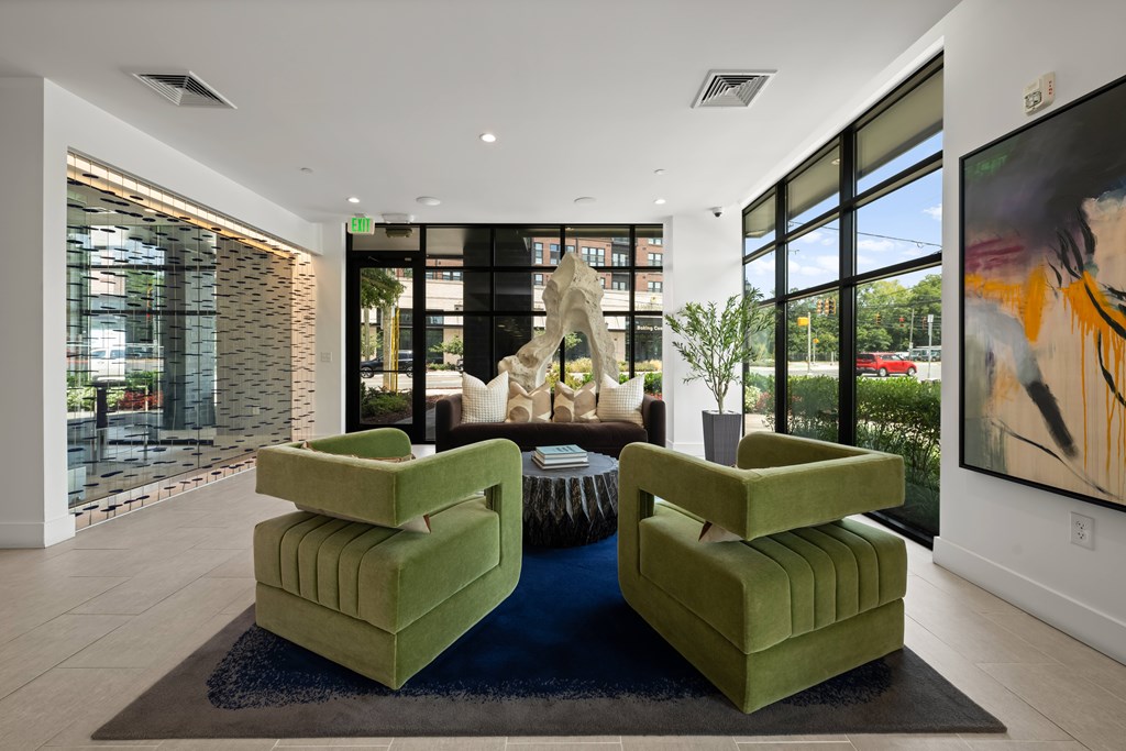 A living room with green chairs and a large painting on the wall.