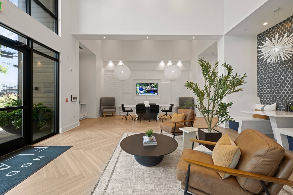 A living room with a brown leather couch and a television mounted on the wall.
