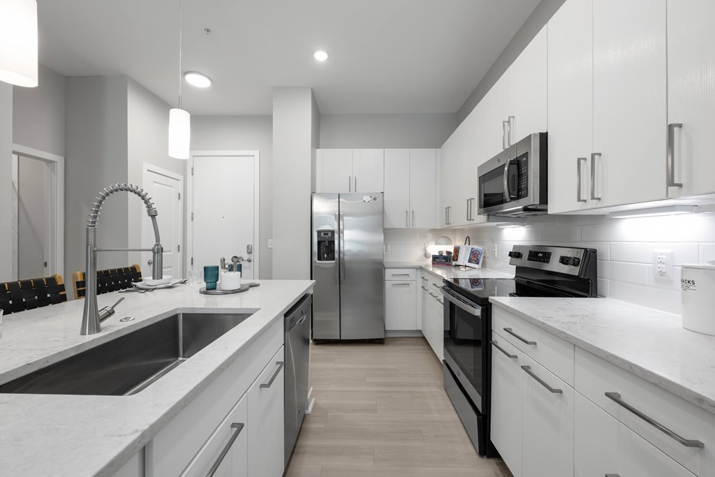 A modern kitchen with white cabinets and stainless steel appliances.