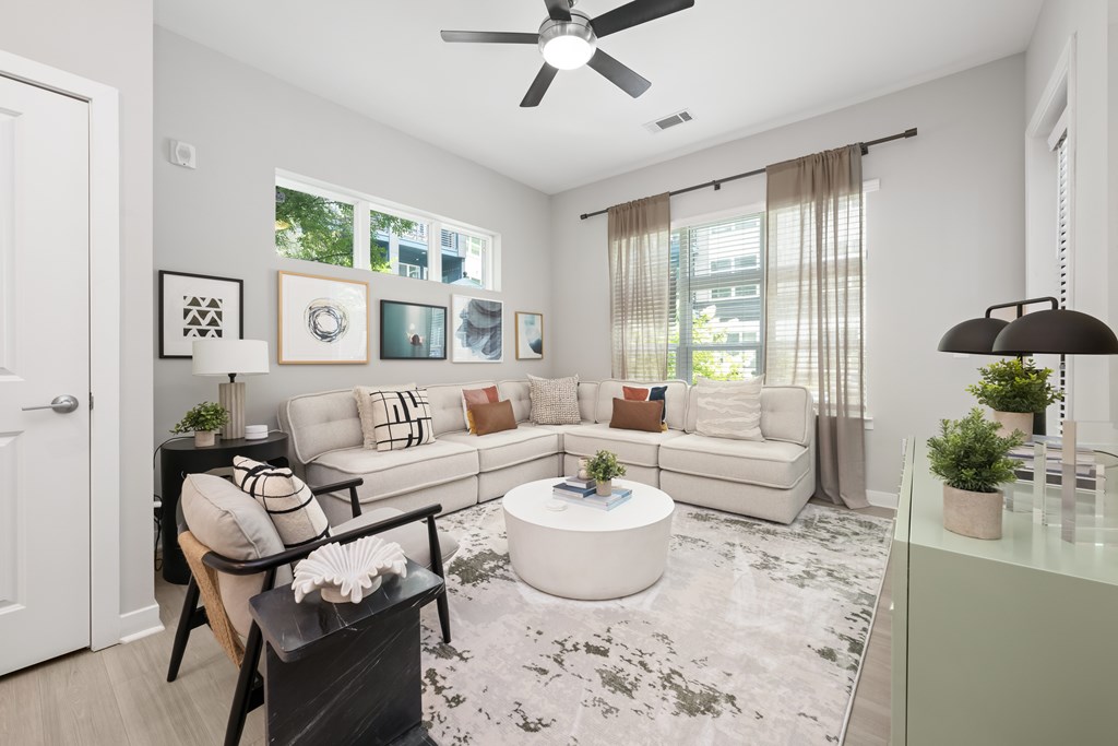 A living room with a white couch, a coffee table, and a ceiling fan.