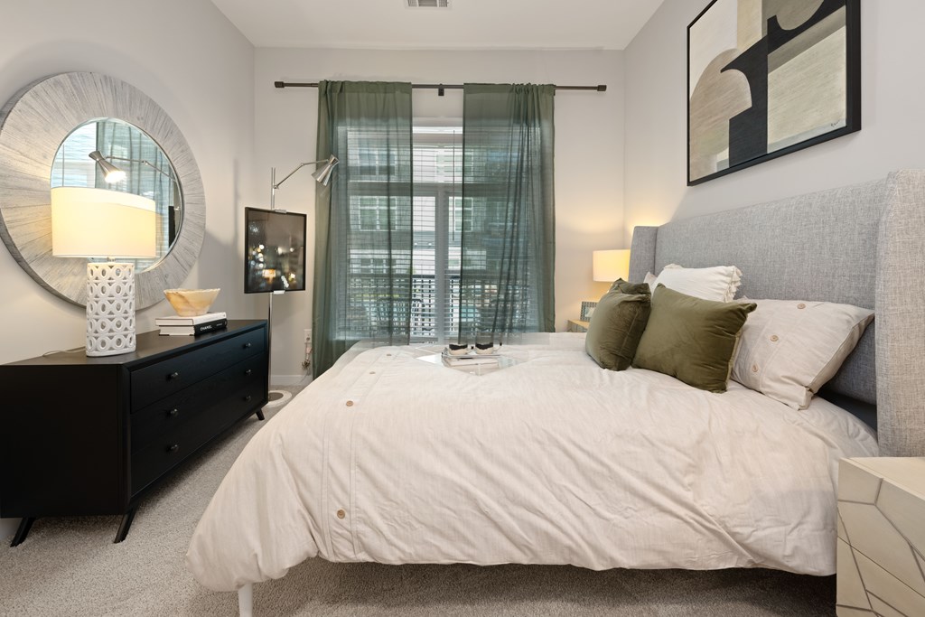 A bedroom with a large bed, a dresser, and a mirror.