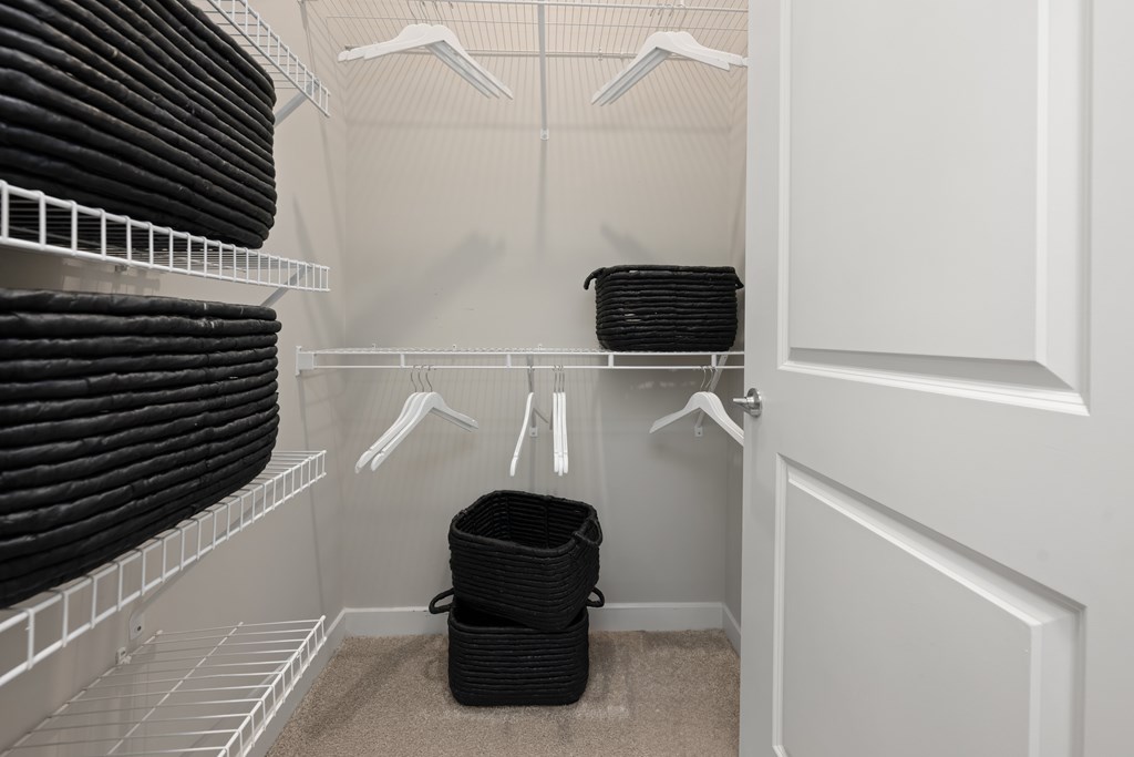A white closet with black bags and hangers.