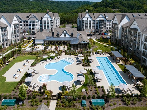 Aerial view of the resort pool, a separate lap pool, sun deck, and clubhouse framed by four-story residential buildings.