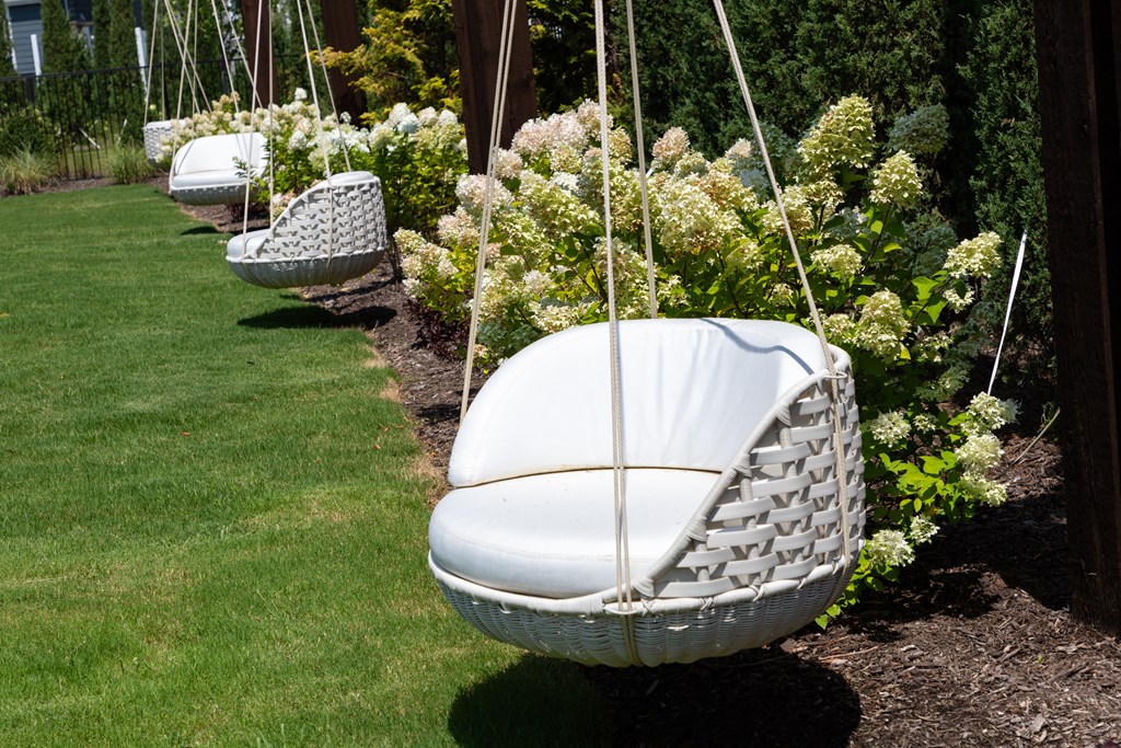 three hanging hammock chairs in a garden