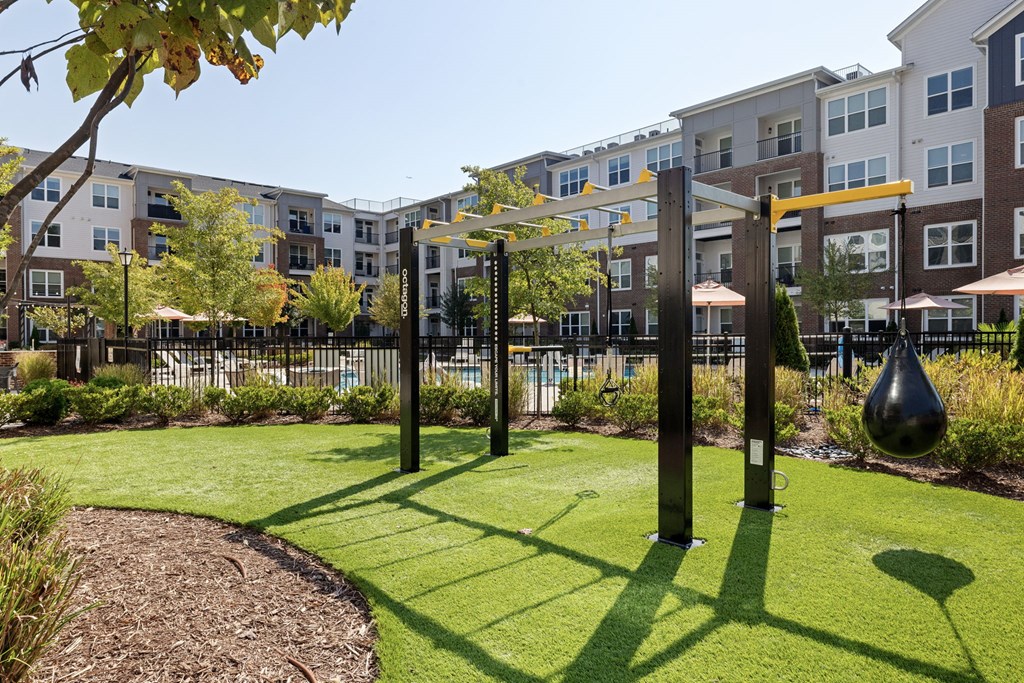 A playground with a swing set and a slide in the foreground and apartment buildings in the background.