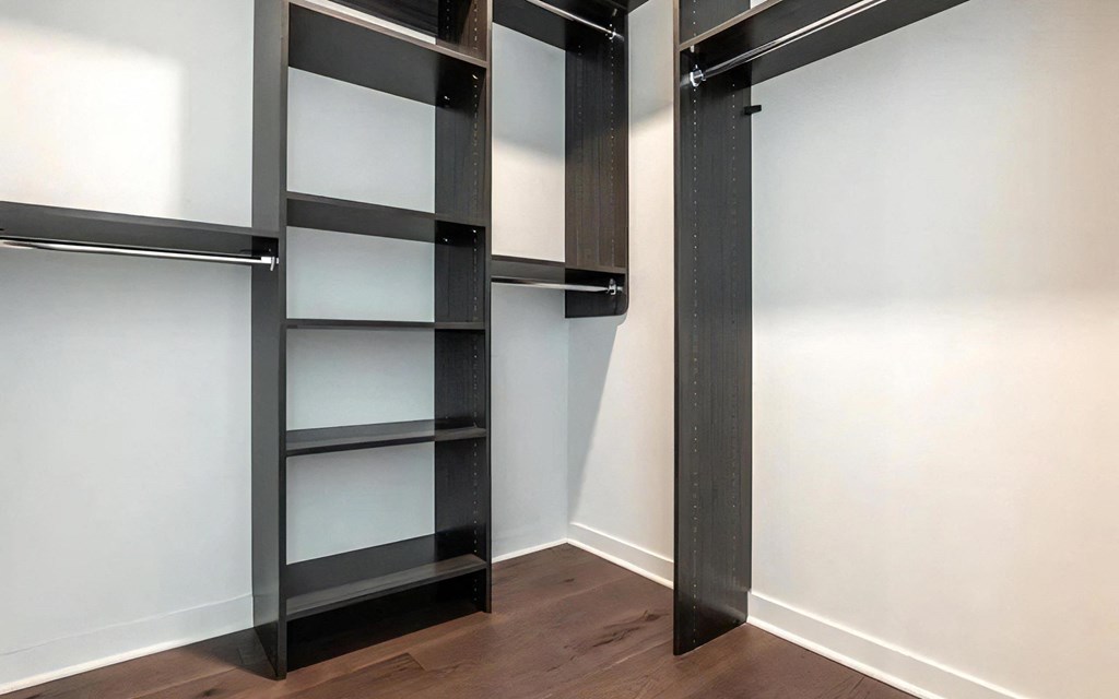 Spacious Apartment Walk-In Closet Featuring Built-In Shelves and Dark Wood Tones