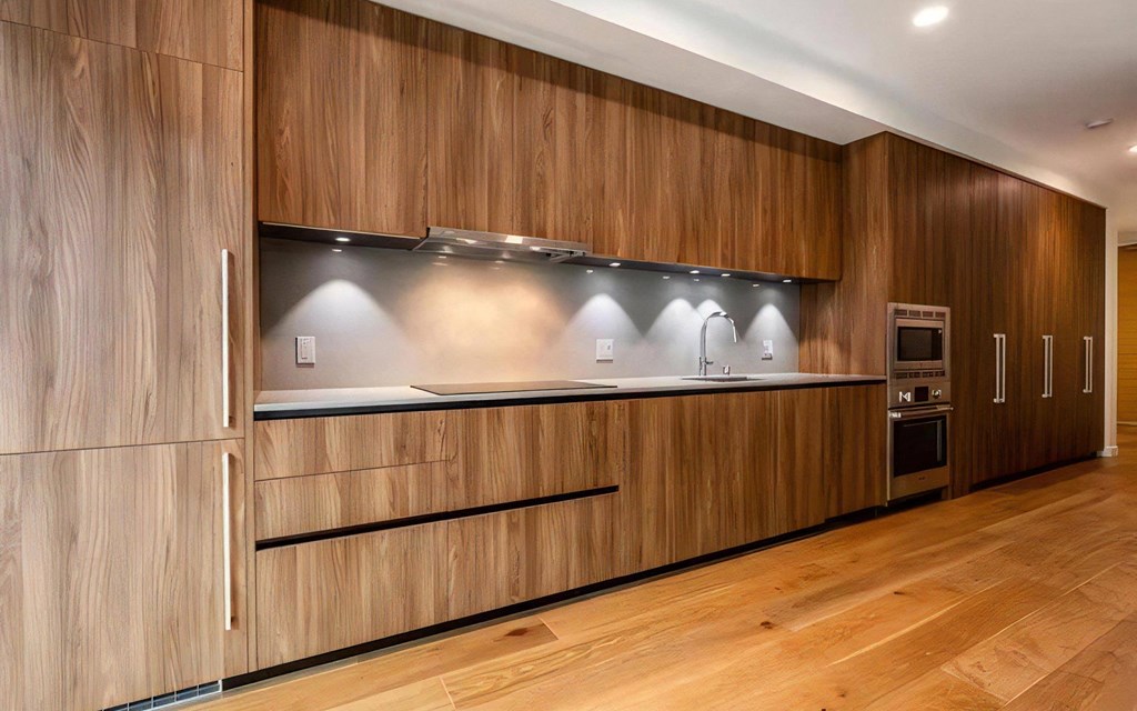 Apartment Kitchen with Wood Cabinets, Cooktop, and Under-Cabinet Lighting