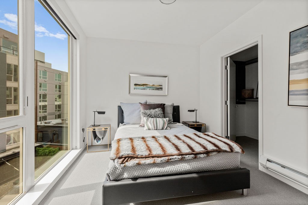 A bedroom with a large bed and a view of a cityscape outside the window.