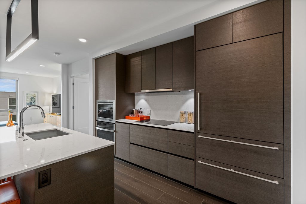 A modern kitchen with brown cabinets and a white countertop.