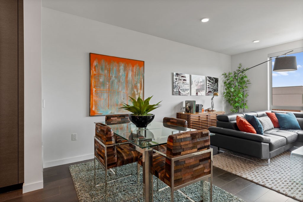 A modern living room with a glass coffee table and a grey couch.