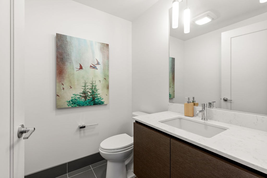 A bathroom with a toilet, sink, and a painting of birds on the wall.