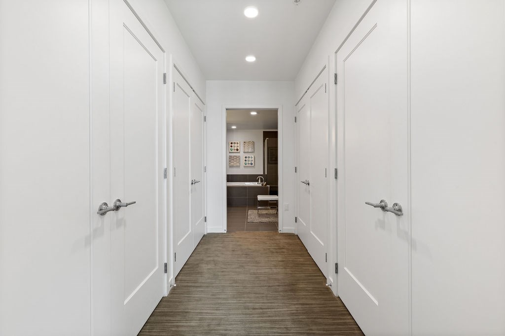 A long hallway with white doors and a wooden floor.