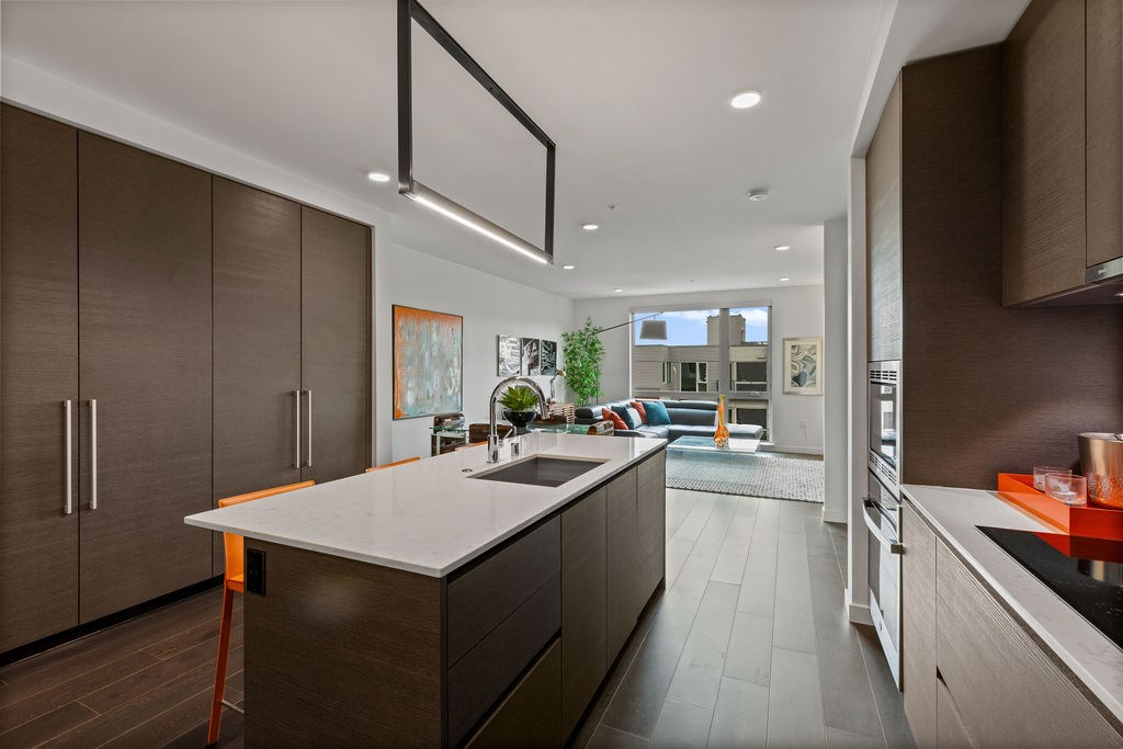 A modern kitchen with a white countertop and dark wood cabinets.